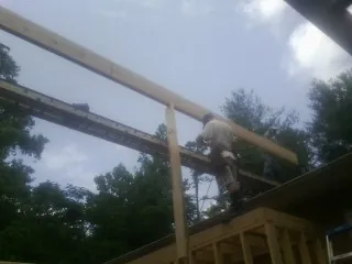 Carpenter setting a ridge beam over a new addition frame — Ice Dam Removal by Roofing Brothers in Garards Fort