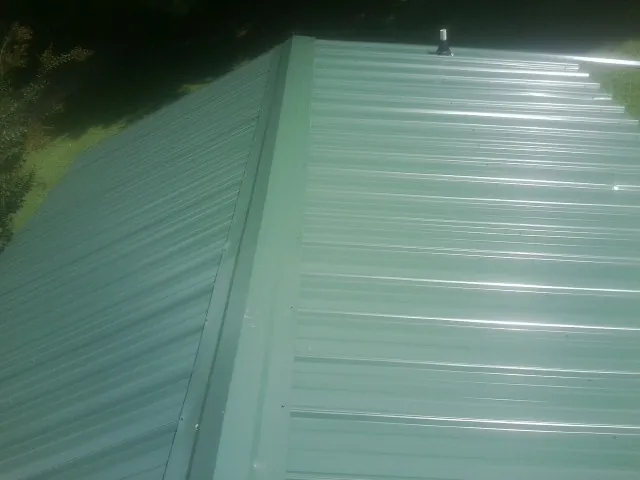 New green metal panels meeting at the ridge of a roof — Flat Roof Repair work by our crew in Garards Fort