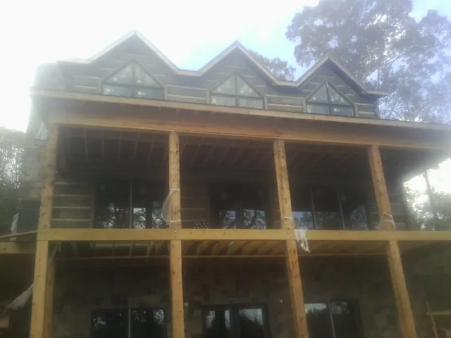 Dormers and porch framing on a large log home under construction — Roof Coating work by our crew in Garards Fort
