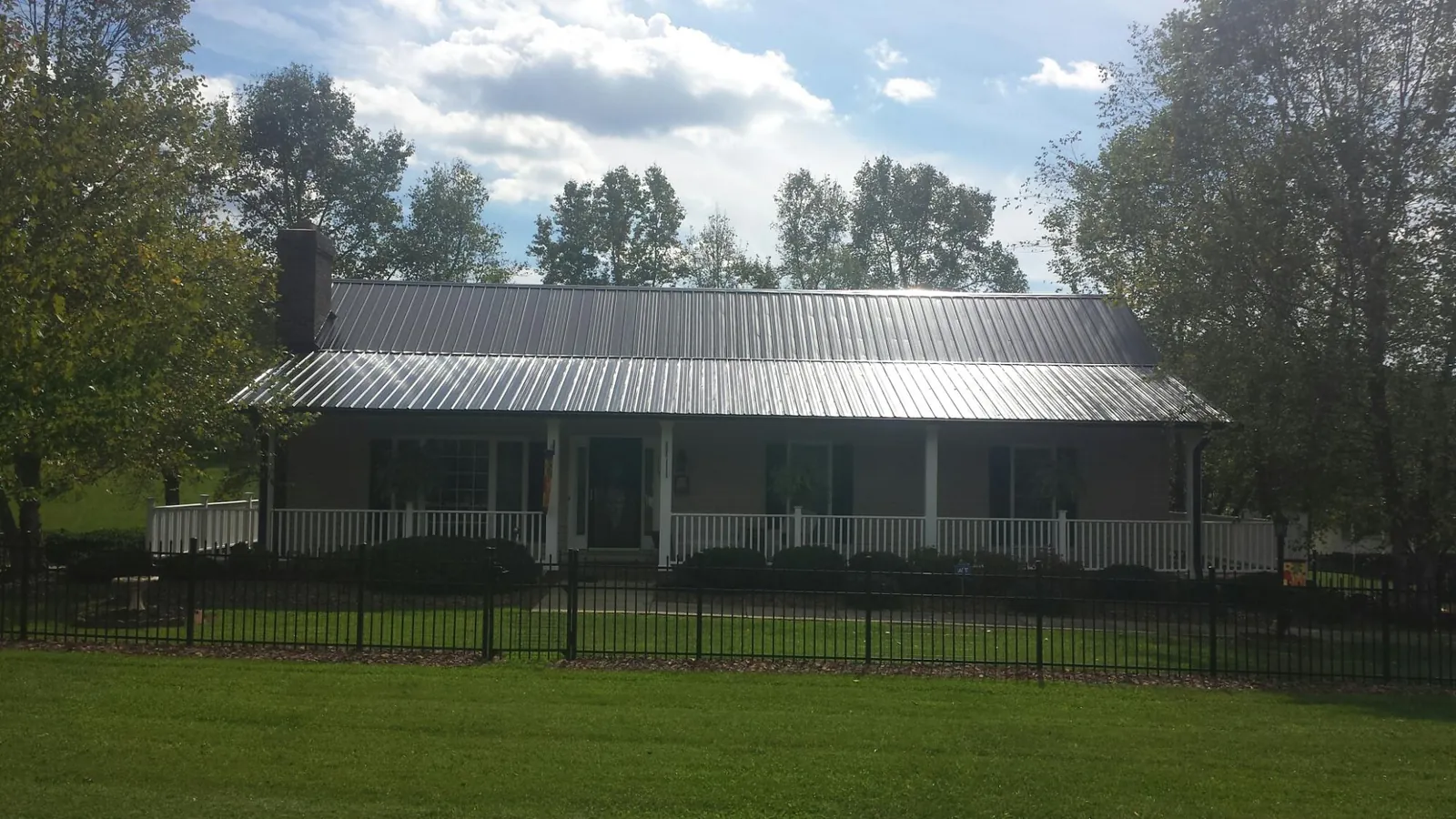 Gray metal roof on a brick ranch with a full width front porch — Gutter Guard Installation work by our crew in Garards Fort