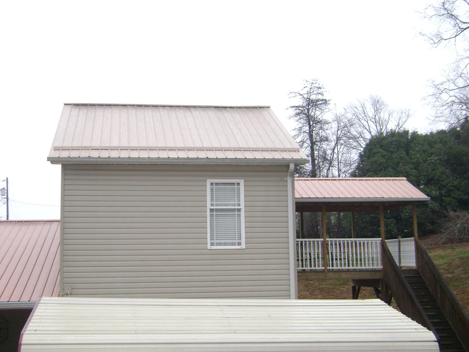 Tan metal roofs on a two story addition and attached porch, from a Roof Replacement job in Garards Fort
