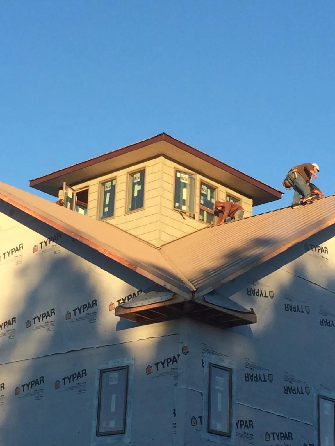 Roofers working around a rooftop cupola on a new metal roof at sunset — Roof Waterproofing in Garards Fort by Roofing Brothers